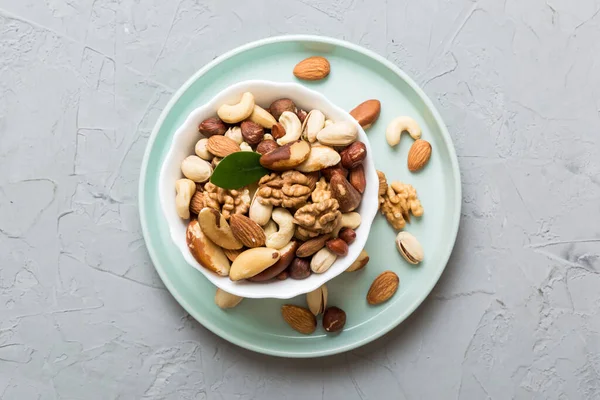 mixed nuts in bowl. Mix of various nuts on colored background. pistachios, cashews, walnuts, hazelnuts, peanuts and brazil nuts.