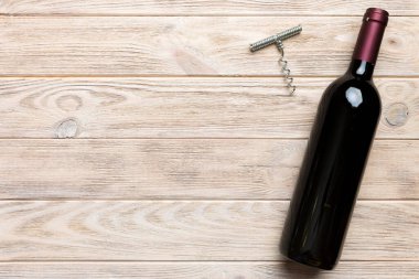 Renkli masada tirbuşonlu bir şişe kırmızı şarap. Düz konum, üst görünüm kopyalama alanı.