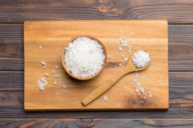 Ahşap bir arka planda ahşap bir kase tuz kristali. Kırsal kaselerdeki tuz, fotokopi alanı olan üst görünüm.