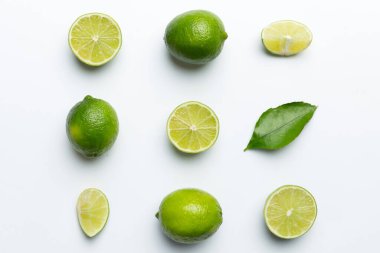 Yeşil yapraklı kireç meyveleri ve beyaz arka planda yarım dilim kesilmiş. Üst Manzara. Kopyalama alanı olan düz.