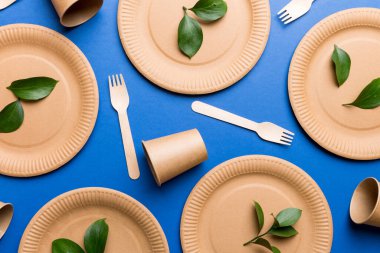 Açık beyaz masa arkaplanındaki boş, tek kullanımlık çevre dostu tabaklar, bardaklar, çatal bıçaklar. Üst Manzara. Biyo-çözünebilir el yapımı yemekler. Geri dönüşüm konsepti. Yakın plan..