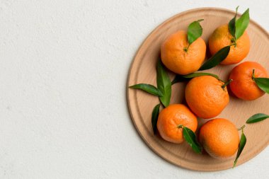 Taze kesilmiş mandalinalar ve renkli arka planda yuvarlak tabaklar. Yemek ve içecek malzemeleri hazırlanıyor. Sağlıklı beslenme teması üst görünüm kopyalama alanı.