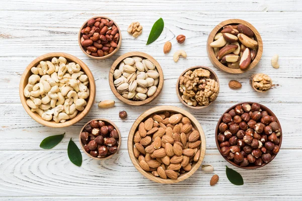 stock image mixed nuts in wooden bowl. Mix of various nuts on colored background. pistachios, cashews, walnuts, hazelnuts, peanuts and brazil nuts.