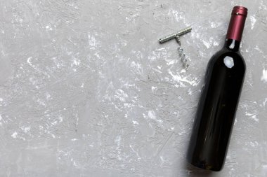 Renkli masada tirbuşonlu bir şişe kırmızı şarap. Düz konum, üst görünüm kopyalama alanı.