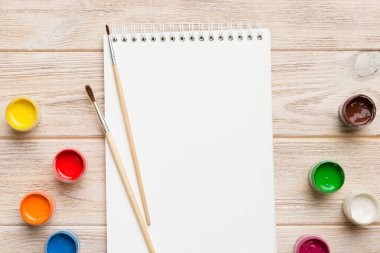 Albüm sayfaları, boyalar, kalemler, renkli arka planda fırçalar. Boşluğu olan üst görünüm. Yaratıcılık için işyeri. ev öğretmenliği kavramı çizimi.