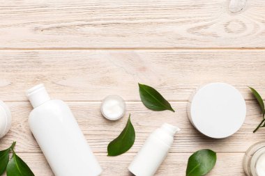 Ahşap zemin üzerinde yeşil yapraklar olan organik kozmetik ürünler. Uzayı kopyala, düz yat.