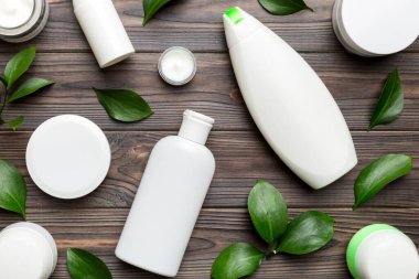 Ahşap zemin üzerinde yeşil yapraklar olan organik kozmetik ürünler. Düz yatıyordu.