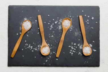 Ahşap arka planda bir sürü tahta kaşıkta tuz. Farklı tuzlu kaşıklar..