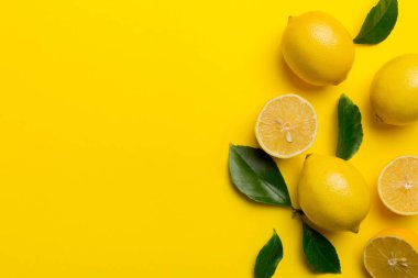 Renkli arka planda yeşil yapraklı taze limonlar, üst görünüm, metin için boşluk.