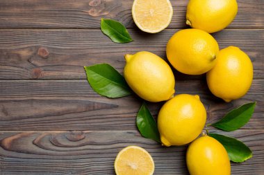 Renkli arka planda yeşil yapraklı taze limonlar, üst görünüm, metin için boşluk.