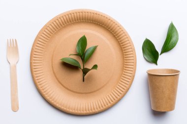 Açık beyaz masa arkaplanındaki boş, tek kullanımlık çevre dostu tabaklar, bardaklar, çatal bıçaklar. Üst Manzara. Biyo-çözünebilir el yapımı yemekler. Geri dönüşüm konsepti. Yakın plan..