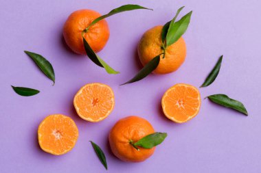 Renkli arkaplanda yeşil yaprakları, üst görünümü, metin için alanı olan bir sürü olgun mandalina..