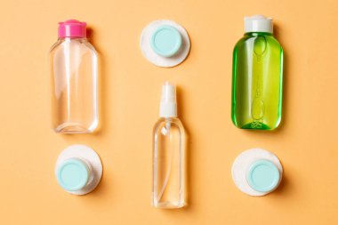 Renkli arka planda seyahat boyutunda kozmetik şişeler. Krema kavanozları düzdü. Vücut bakım stili kavramının en üst görünümü.