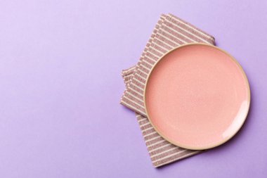 Renkli arka planda üst manzara. Yemek için masa örtüsü üzerine yuvarlak pembe tabak. Tasarımınız için boşluk olan peçeteye boş tabak.