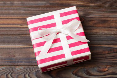 Noel 'i ya da diğer tatil hediyelerini renkli arka planda kurdeleyle renkli kağıda sardım. Şimdiki kutu, renkli tabloda hediye süslemesi, kopya alanı ile üst görünüm.