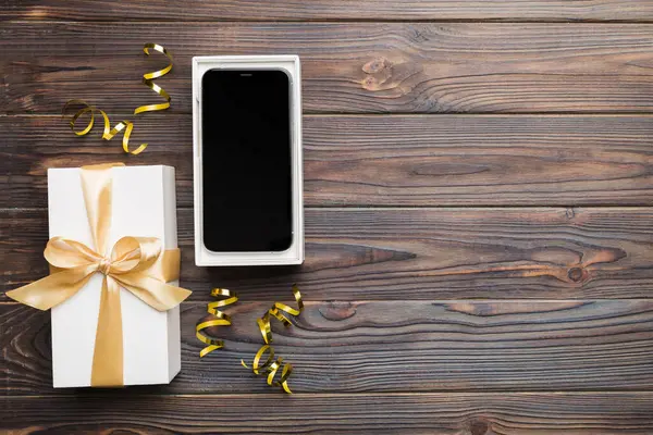 Geöffnete Geschenkbox Mit Goldband Und Smartphone Auf Farbigem Hintergrund Ansicht — Stockfoto
