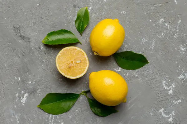 Renkli arka planda yeşil yapraklı taze limonlar, üst görünüm, metin için boşluk.