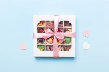 Valentine day composition: sweet candy, with gift boxes with bow and red felt hearts, photo template, background. Top View with copy space.