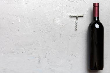 Renkli masada tirbuşonlu bir şişe kırmızı şarap. Düz konum, üst görünüm kopyalama alanı.