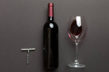 Tirbuşonlu düz kompozisyon, bir şişe şarap ve renkli masada zarif bir cam. Düz konum, üst görünüm kopyalama alanı.