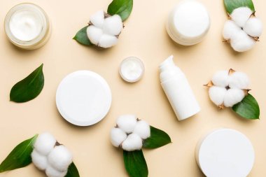 Pamuk çiçekli organik kozmetik ürünler ve ahşap arka planda yeşil yapraklar. Düz yatıyordu.