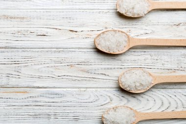 Ahşap arka planda bir sürü tahta kaşıkta tuz. Farklı tuzlu kaşıklar..