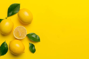 Renkli arka planda yeşil yapraklı taze limonlar, üst görünüm, metin için boşluk.