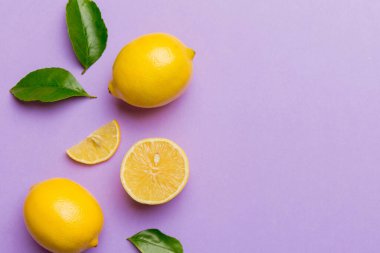 Renkli arka planda yeşil yapraklı taze limonlar, üst görünüm, metin için boşluk.