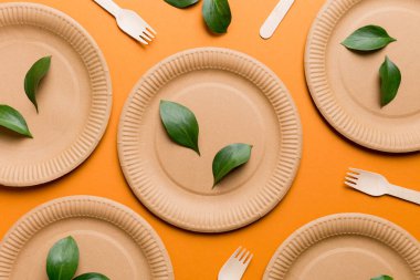 Açık beyaz masa arkaplanındaki boş, tek kullanımlık çevre dostu tabaklar, bardaklar, çatal bıçaklar. Üst Manzara. Biyo-çözünebilir el yapımı yemekler. Geri dönüşüm konsepti. Yakın plan..