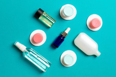 Yüz bakımı için en iyi bakış açısı: şişeler ve kavanozlar dolusu tonik, su, krem, renkli arka planda pamuk pedleri. Fikirleriniz için boş midye içeren vücut bakım konsepti.