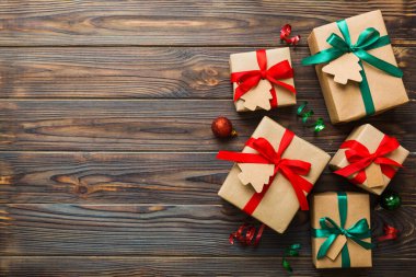 wrapped christmas or other holiday handmade present in paper with colored ribbon. Present box, decoration of gift on colourfull table, top view with copy space.