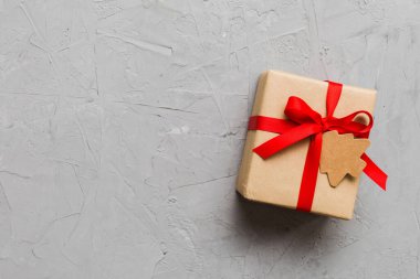 wrapped christmas or other holiday handmade present in paper with colored ribbon. Present box, decoration of gift on colourfull table, top view with copy space.