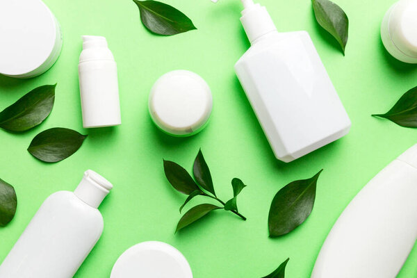 Organic cosmetic products with green leaves on color background. Flat lay.