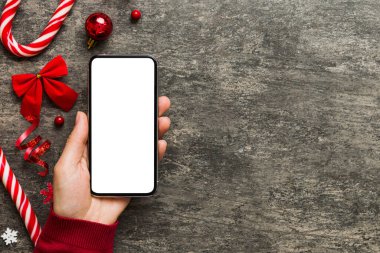 Mesaj atmak için yeri olan bir Noel modeli. Noel reklamı, uygulama şablonu. Masa arkasında boş ekran olan el ele tutuşan telefon. Mutlu yıllar ve Xmas Flat.