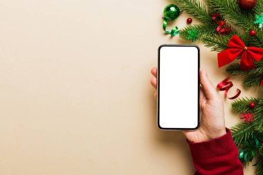 Mesaj atmak için yeri olan bir Noel modeli. Noel reklamı, uygulama şablonu. Masa arkasında boş ekran olan el ele tutuşan telefon. Mutlu yıllar ve Xmas Flat.
