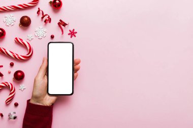 Mesaj atmak için yeri olan bir Noel modeli. Noel reklamı, uygulama şablonu. Masa arkasında boş ekran olan el ele tutuşan telefon. Mutlu yıllar ve Xmas Flat.