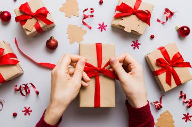 Kadınlar Noel tatili için sürpriz hediyeler hazırlıyor. İş yerinde el aletleri ve manzarayla oturuyor. Renkli masada Noel hediyesini paketleyen kadın..