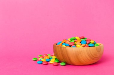 Renkli arka planda bir kasede çok renkli şekerler. Doğum günü ve tatil konsepti. Kopyalama alanı olan üst görünüm.