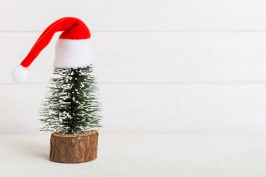One small Christmas tree with santa hat on colored background. new year decoration with copy space.