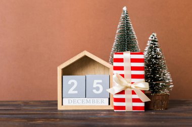 25 december. Christmas composition on colored background with a wooden calendar, with a gift box, toys, bauble copy space.