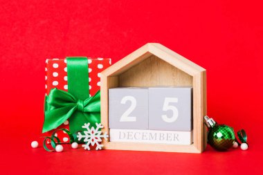 25 december. Christmas composition on colored background with a wooden calendar, with a gift box, toys, bauble copy space.