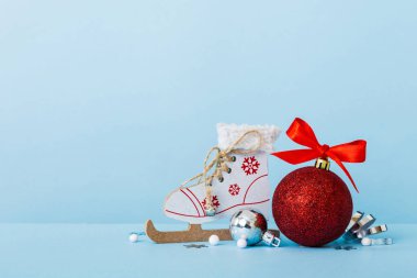 Christmas ball with skates on colored background. decoration bauble with ribbon bow with copy space.