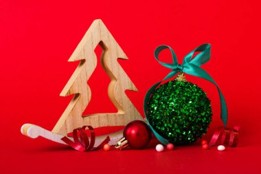 Christmas ball with decorative wooden tree on colored background. decoration bauble with ribbon bow with copy space.