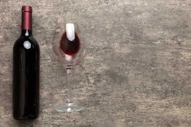 Bir bardak kırmızı şarap ve renkli masada bir şişe. Düz konum, üst görünüm kopyalama alanı.