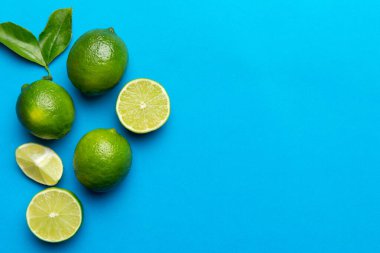 Yeşil yapraklı kireç meyveleri ve beyaz arka planda yarım dilim kesilmiş. Üst Manzara. Kopyalama alanı olan düz.