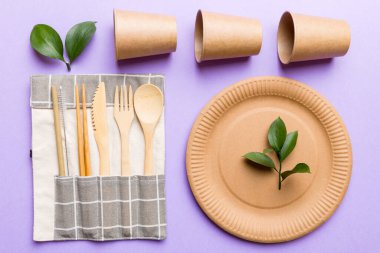 Açık beyaz masa arkaplanındaki boş, tek kullanımlık çevre dostu tabaklar, bardaklar, çatal bıçaklar. Üst Manzara. Biyo-çözünebilir el yapımı yemekler. Geri dönüşüm konsepti. Yakın plan..