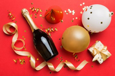 Renkli arka planda şampanya şişesi hediye paketi kurdeleleri ve konfetilerin düz kompozisyonu vardı. Düz konum, üst görünüm tatil konsepti.
