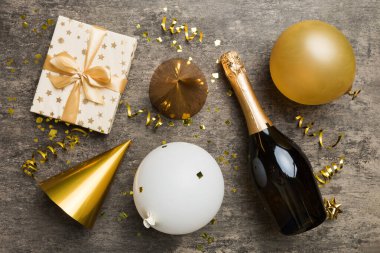 Renkli arka planda şampanya şişesi hediye paketi kurdeleleri ve konfetilerin düz kompozisyonu vardı. Düz konum, üst görünüm tatil konsepti.