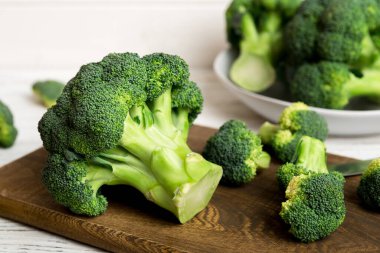 Tahta kesme tahtasının üzerinde bıçakla taze yeşil brokoli. Brokoli lahana yaprakları. Hafif arkaplan. Düz yatıyordu.