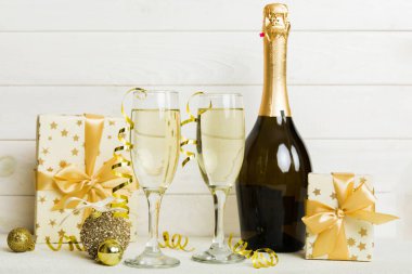 Champagne bottle with confetti, glasses and christmas decor on colored holiday background. Flat lay New Year decorations.